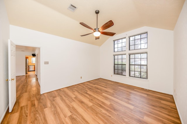 spare room with ceiling fan, vaulted ceiling, and light hardwood / wood-style flooring