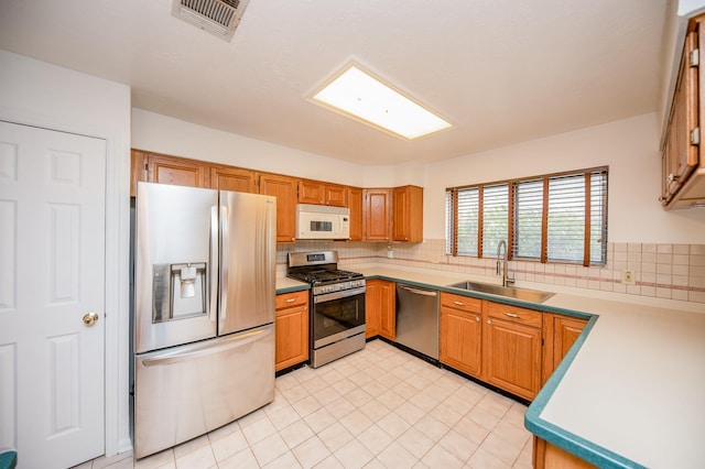 kitchen featuring stainless steel appliances, sink, and decorative backsplash