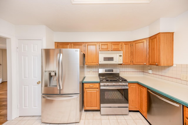 kitchen featuring appliances with stainless steel finishes, light tile patterned floors, and decorative backsplash