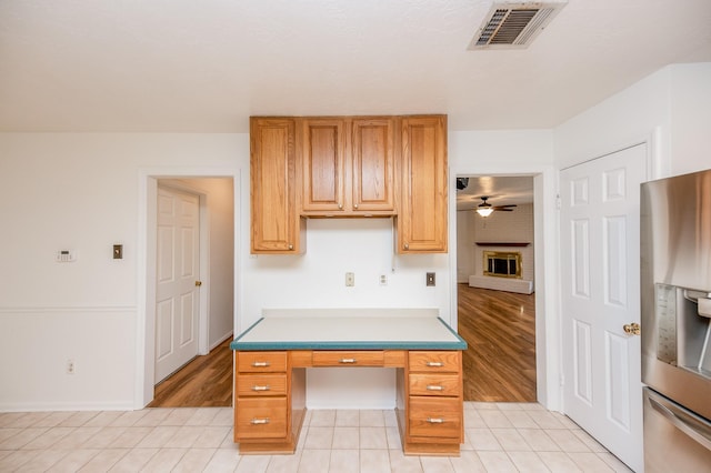 kitchen with stainless steel fridge with ice dispenser, a fireplace, ceiling fan, and light tile patterned flooring