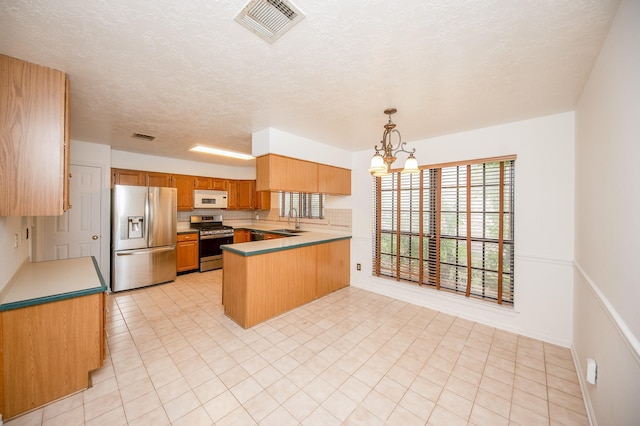 kitchen featuring pendant lighting, tasteful backsplash, sink, kitchen peninsula, and stainless steel appliances