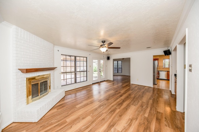 unfurnished living room with hardwood / wood-style flooring, a fireplace, a textured ceiling, and crown molding