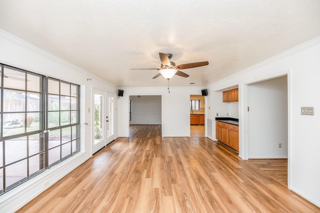 unfurnished living room with ornamental molding, a textured ceiling, ceiling fan, and light hardwood / wood-style flooring