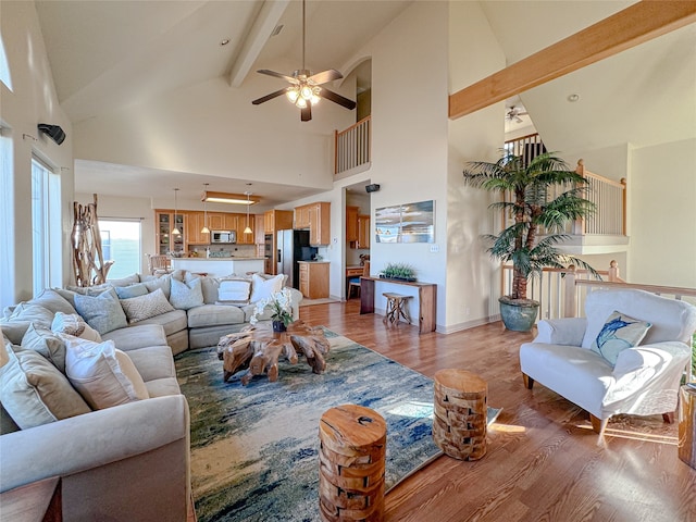 living room featuring ceiling fan, beamed ceiling, light hardwood / wood-style floors, and high vaulted ceiling