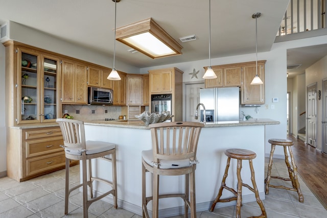 kitchen with a kitchen bar, light hardwood / wood-style flooring, appliances with stainless steel finishes, and tasteful backsplash