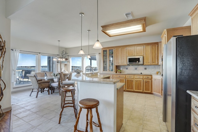 kitchen featuring tasteful backsplash, light stone counters, a breakfast bar, stainless steel appliances, and decorative light fixtures