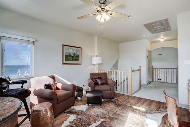 living room featuring a water view, light hardwood / wood-style flooring, and ceiling fan