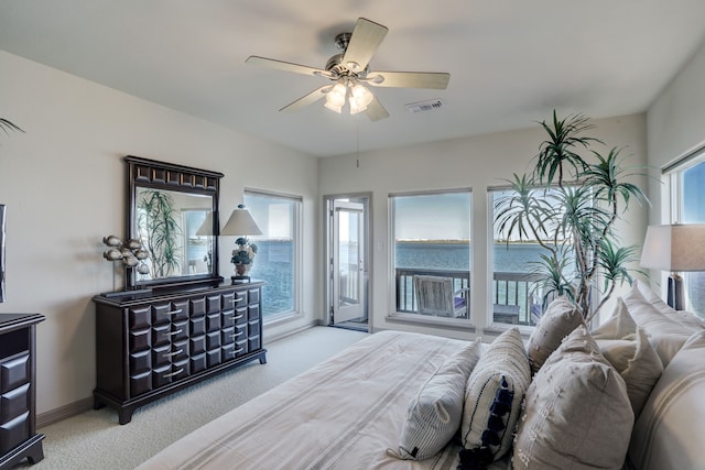 carpeted bedroom with access to exterior, ceiling fan, a water view, and multiple windows