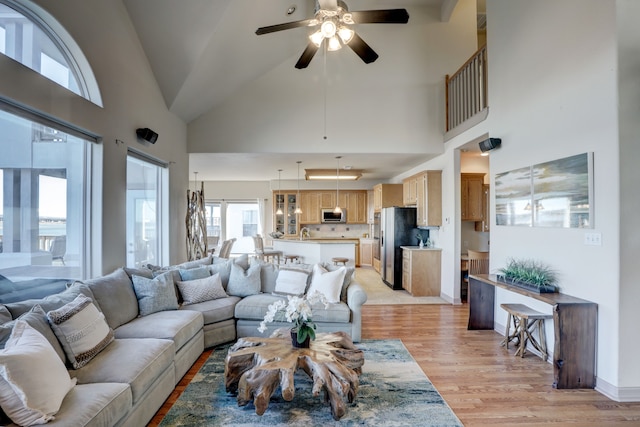 living room featuring ceiling fan, light hardwood / wood-style floors, and high vaulted ceiling