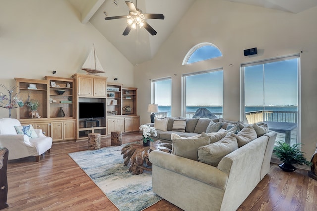 living room with ceiling fan, dark hardwood / wood-style flooring, high vaulted ceiling, and beamed ceiling