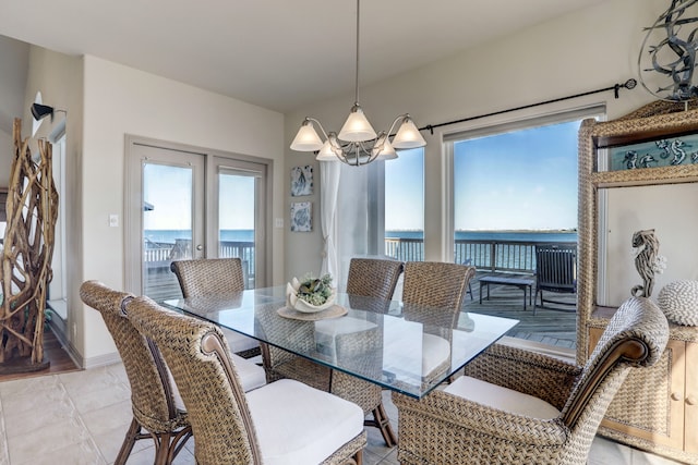 dining area featuring a water view, light tile patterned flooring, and a notable chandelier