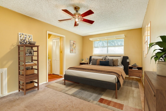 carpeted bedroom featuring ceiling fan and a textured ceiling