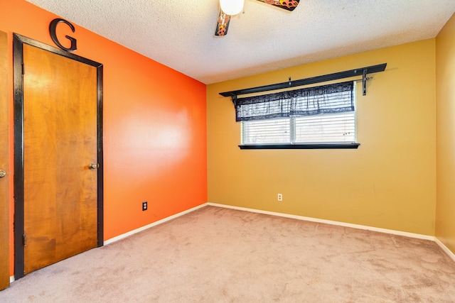 carpeted spare room featuring ceiling fan and a textured ceiling