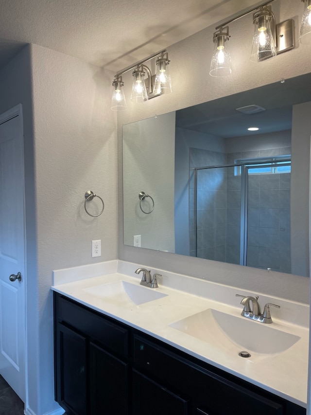 bathroom featuring a textured ceiling and dual bowl vanity