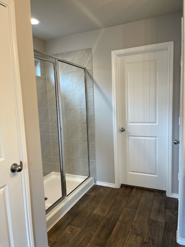 bathroom featuring wood-type flooring and a shower with shower door