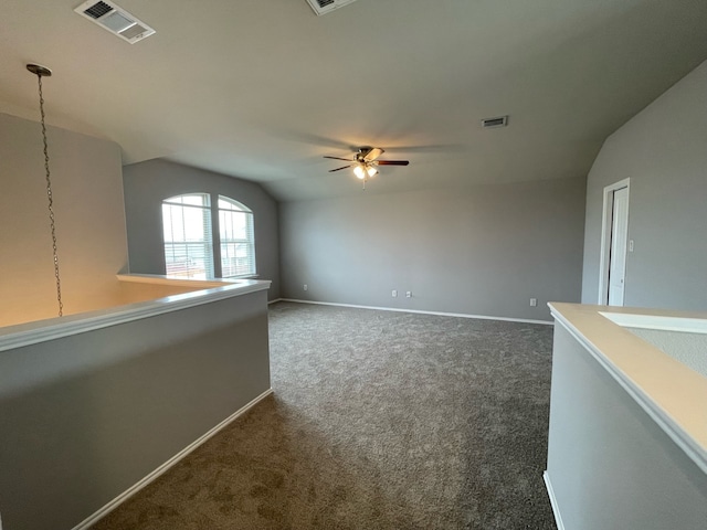 empty room featuring ceiling fan, vaulted ceiling, and dark colored carpet