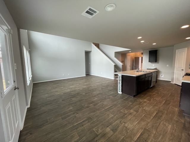 interior space with sink, a kitchen island with sink, and dark hardwood / wood-style flooring