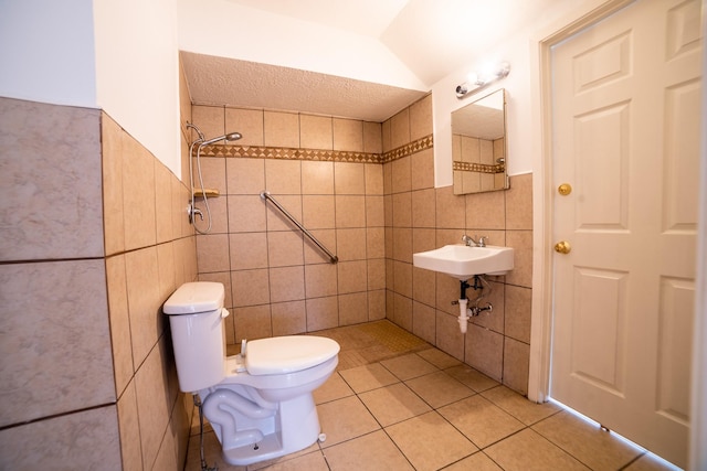 bathroom with toilet, lofted ceiling, tile walls, tile patterned floors, and tiled shower