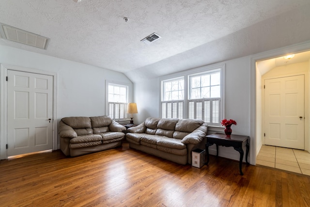 living room with lofted ceiling, wood-type flooring, and a textured ceiling