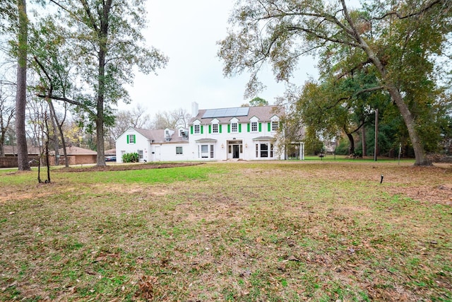 view of front of house with a front yard and solar panels