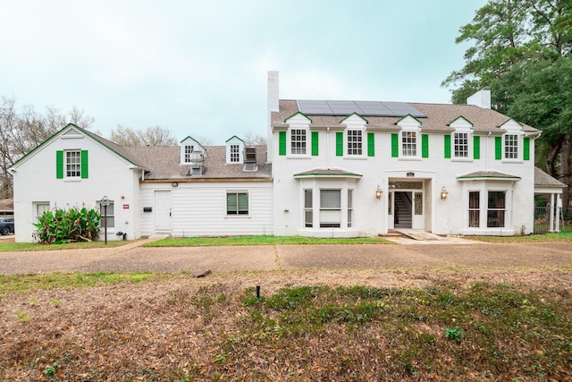 view of front of home with a front lawn and solar panels