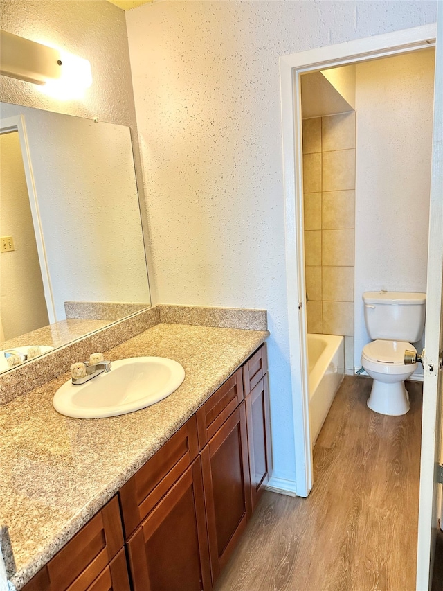 full bathroom with tiled shower / bath combo, vanity, toilet, and wood-type flooring