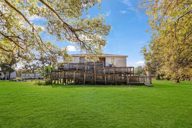 rear view of house with a wooden deck and a lawn