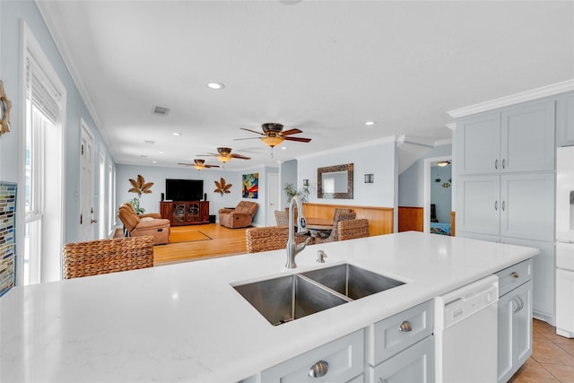 kitchen with light tile patterned flooring, sink, wood walls, ornamental molding, and dishwasher