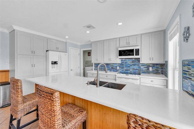 kitchen with sink, crown molding, light tile patterned floors, a kitchen breakfast bar, and white appliances