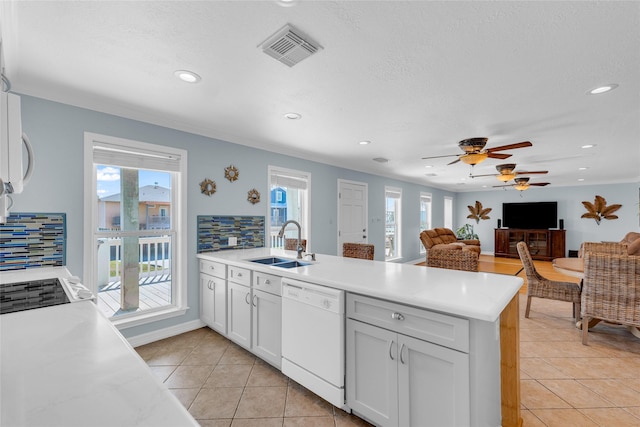 kitchen with sink, white cabinets, decorative backsplash, light tile patterned floors, and white dishwasher