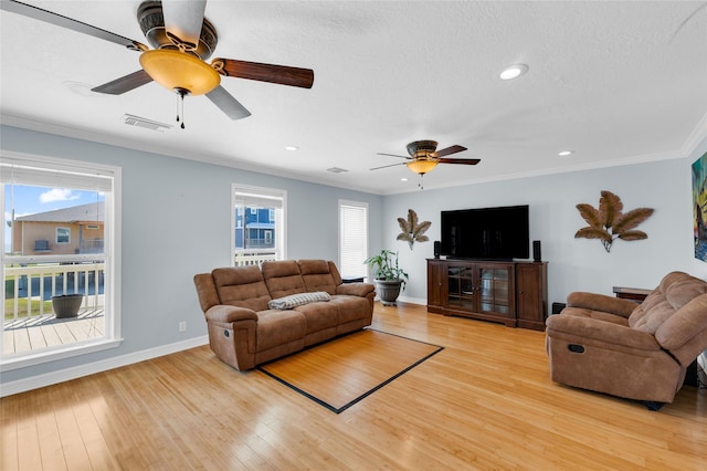 living room featuring crown molding, a healthy amount of sunlight, and light wood-type flooring