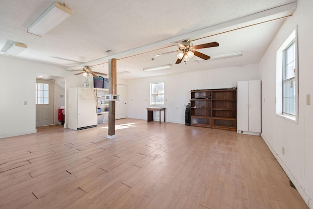 unfurnished living room featuring a textured ceiling, ceiling fan, and light hardwood / wood-style floors