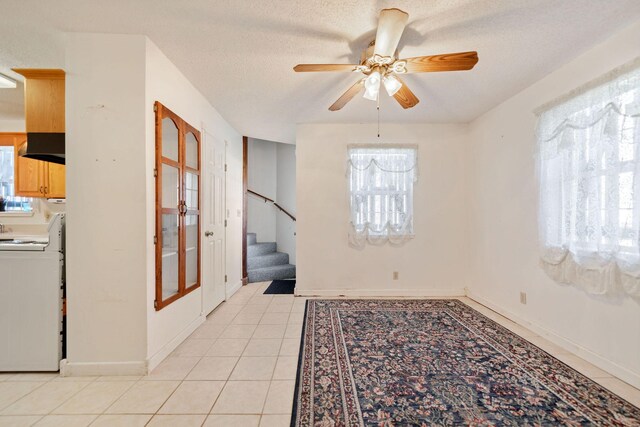 tiled spare room featuring a textured ceiling, ceiling fan, and a healthy amount of sunlight