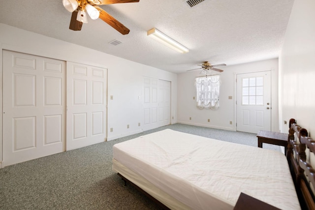 bedroom featuring a textured ceiling, multiple closets, carpet, and ceiling fan