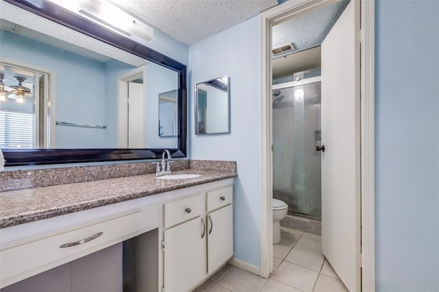 bathroom with tile patterned flooring, toilet, vanity, visible vents, and a stall shower