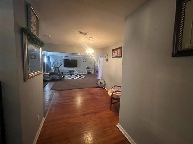 hallway featuring dark wood-type flooring and an inviting chandelier