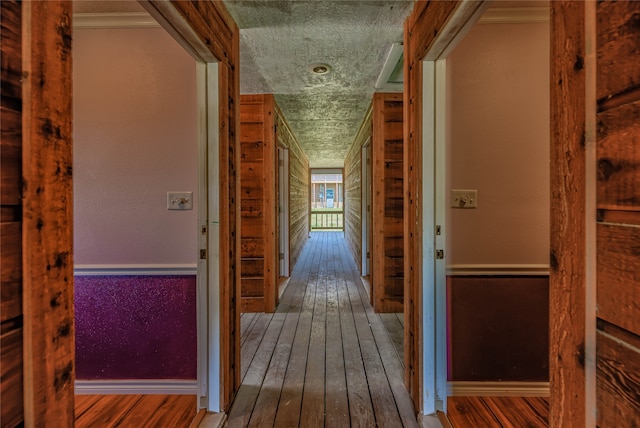 hallway with crown molding, wood-type flooring, and a textured ceiling