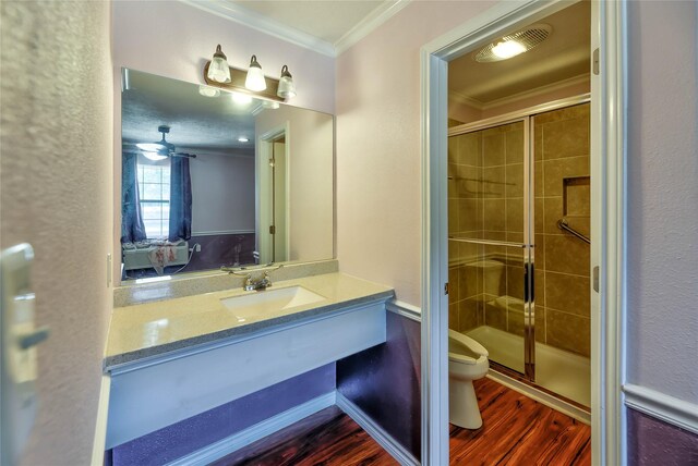 bathroom with ceiling fan, toilet, an enclosed shower, hardwood / wood-style floors, and crown molding