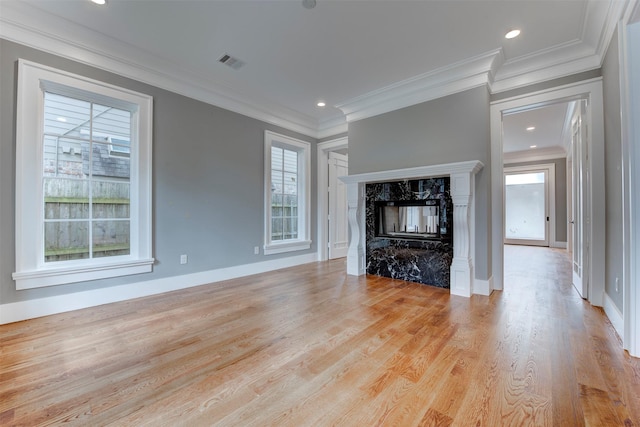 unfurnished living room featuring ornamental molding, a high end fireplace, and light wood-type flooring