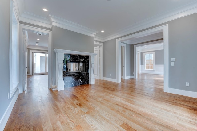 unfurnished living room featuring crown molding, a fireplace, and light wood-type flooring