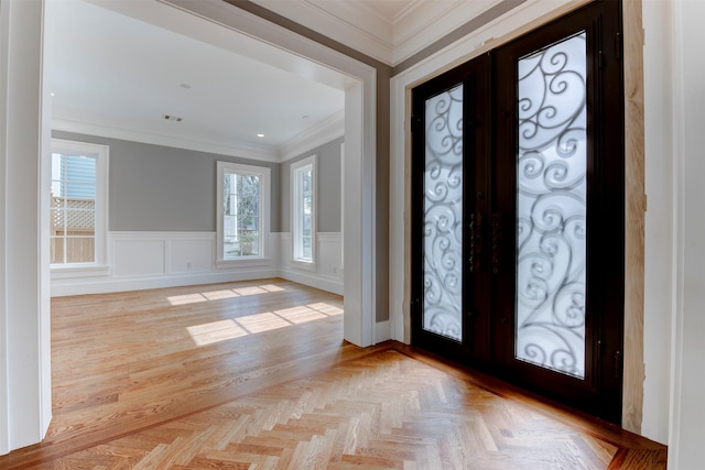 foyer entrance featuring crown molding, light parquet flooring, and french doors