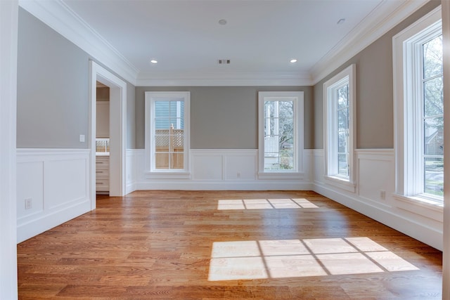 unfurnished room with crown molding, plenty of natural light, and light hardwood / wood-style flooring