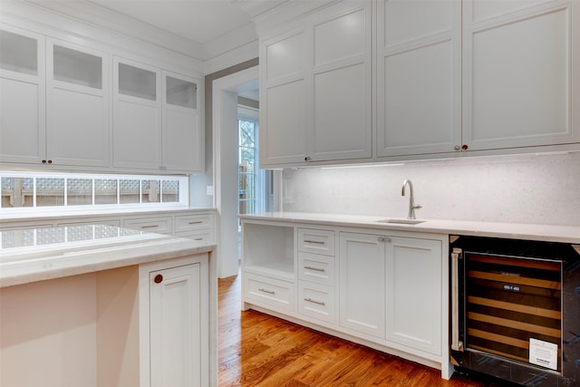 kitchen featuring sink, light hardwood / wood-style flooring, beverage cooler, decorative backsplash, and white cabinets