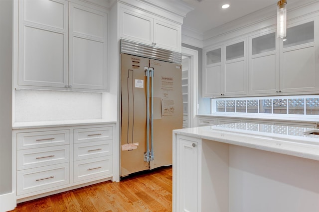 kitchen featuring light hardwood / wood-style floors, built in fridge, hanging light fixtures, and white cabinets