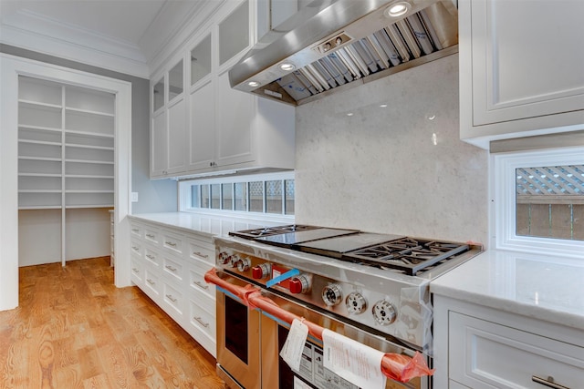 kitchen with range with two ovens, white cabinetry, wall chimney range hood, and light hardwood / wood-style floors