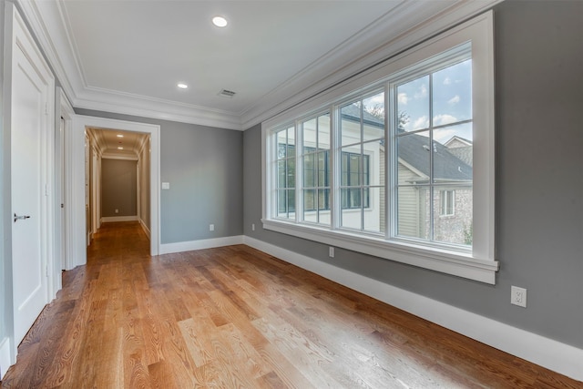 empty room with ornamental molding and light hardwood / wood-style flooring