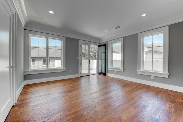 empty room featuring wood-type flooring, ornamental molding, and french doors