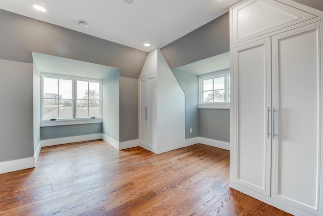 bonus room with lofted ceiling and light wood-type flooring