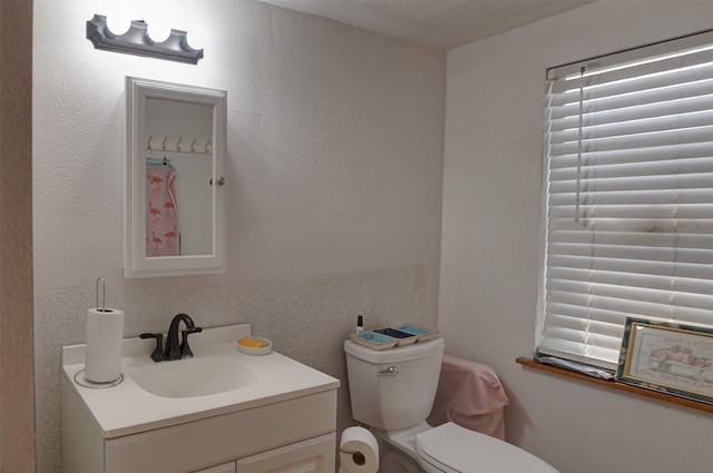 bathroom featuring a textured ceiling, vanity, and toilet