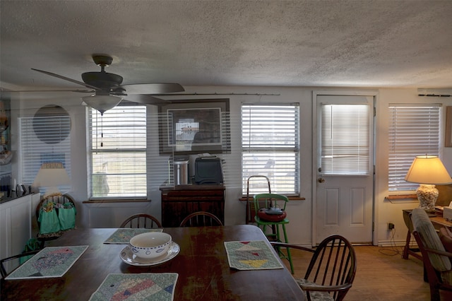 dining space featuring a textured ceiling, wood-type flooring, and ceiling fan